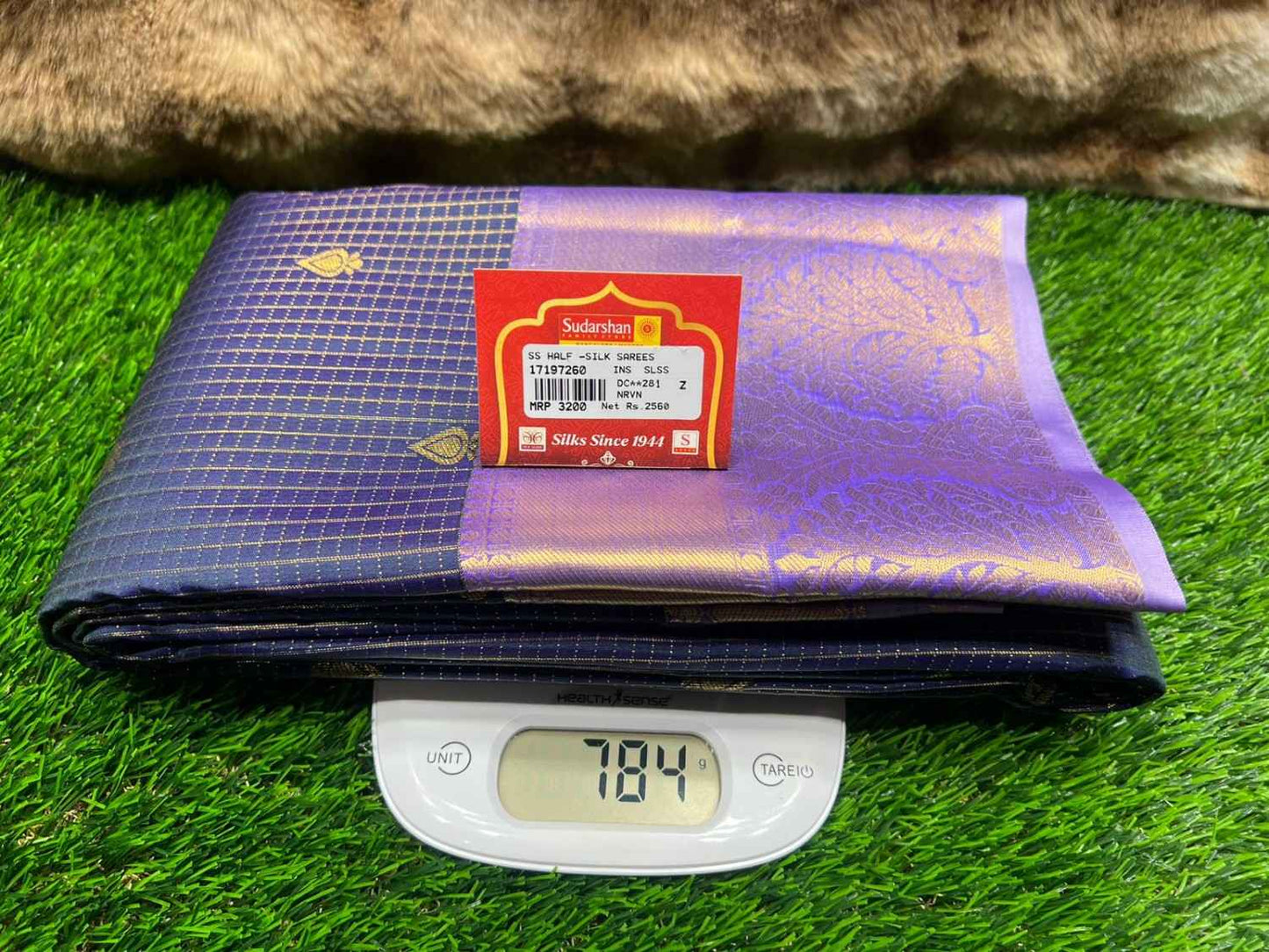 Purple fabric with a brand label on a digital scale against a grassy background