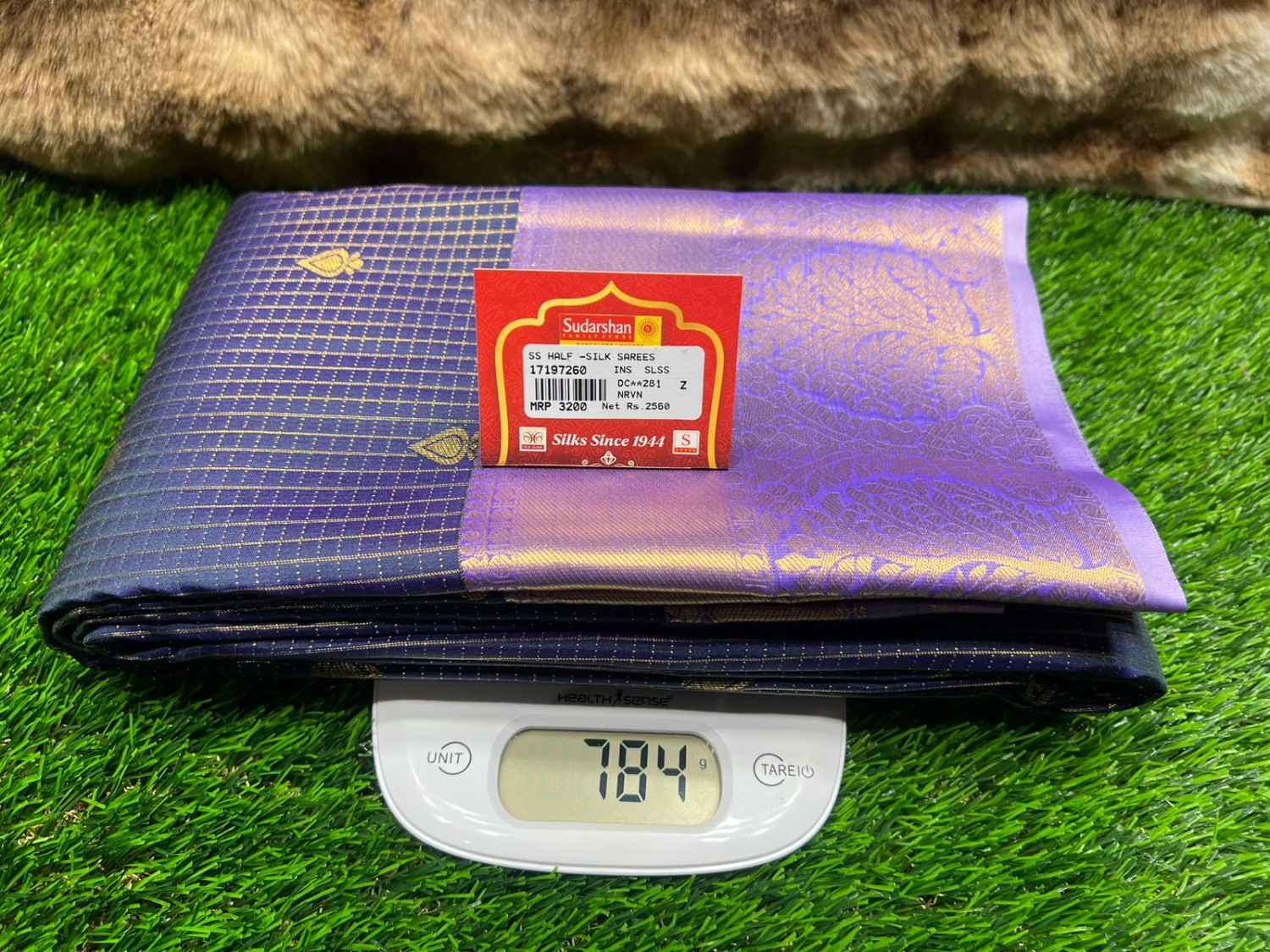 Purple fabric with a brand label on a digital scale against a grassy background