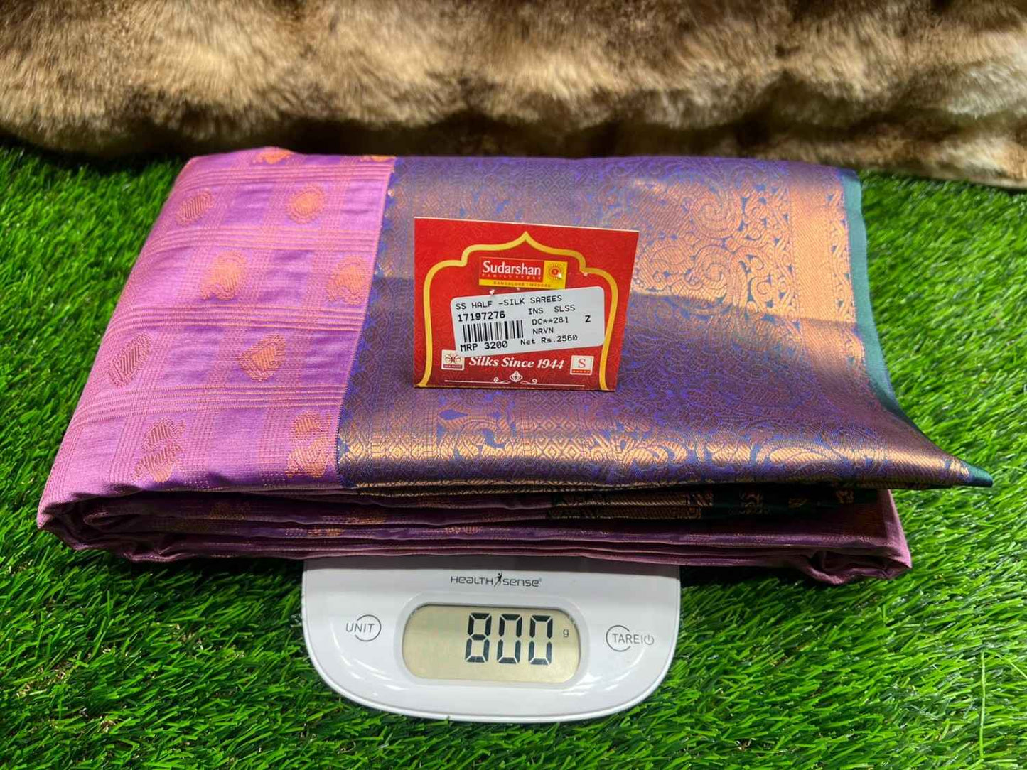 Purple fabric with a brand label on a digital scale against a grassy background