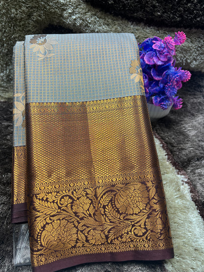 Brown saree with gold patterns on a textured surface with purple flowers.
