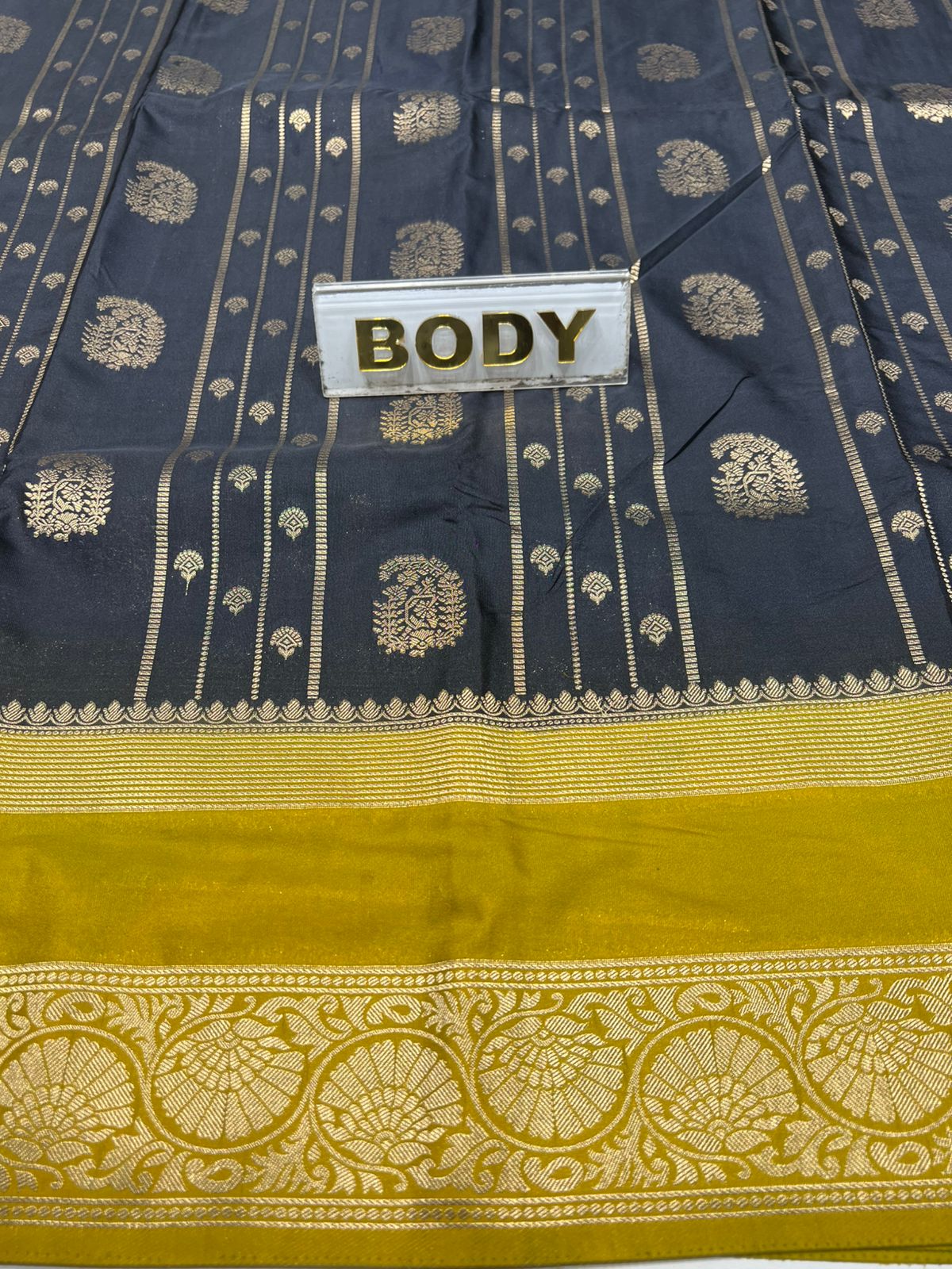 Navy blue and yellow saree with intricate patterns and a visible label.