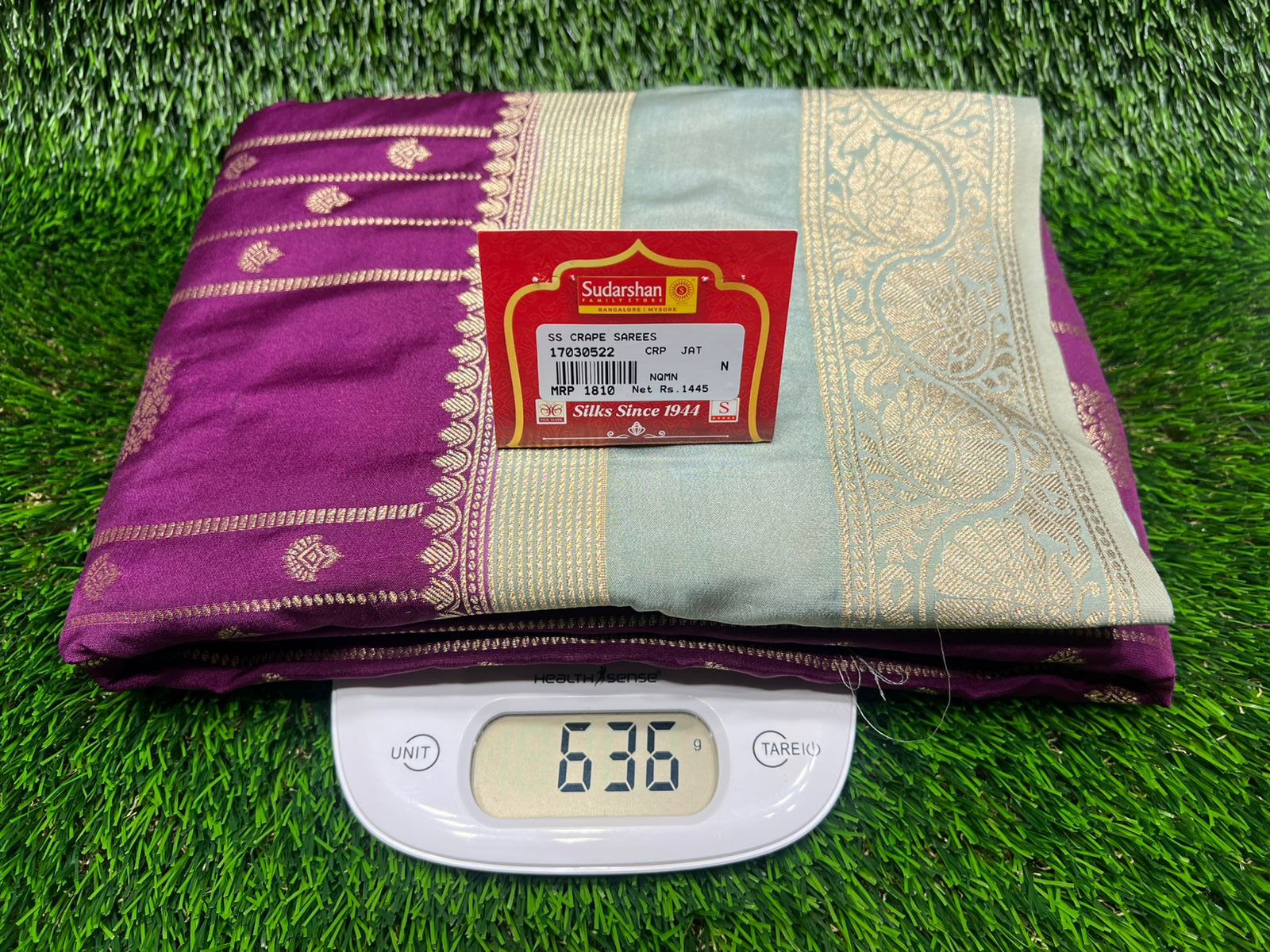Purple and green fabric with a digital weight scale on grass