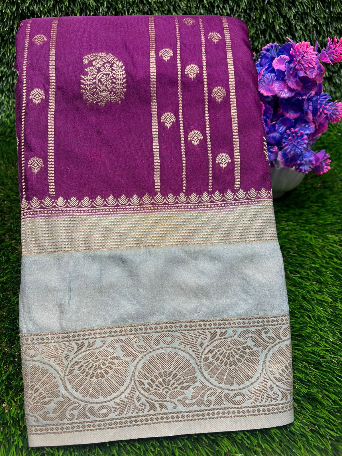 Purple and beige saree with floral decorations on a green grass background