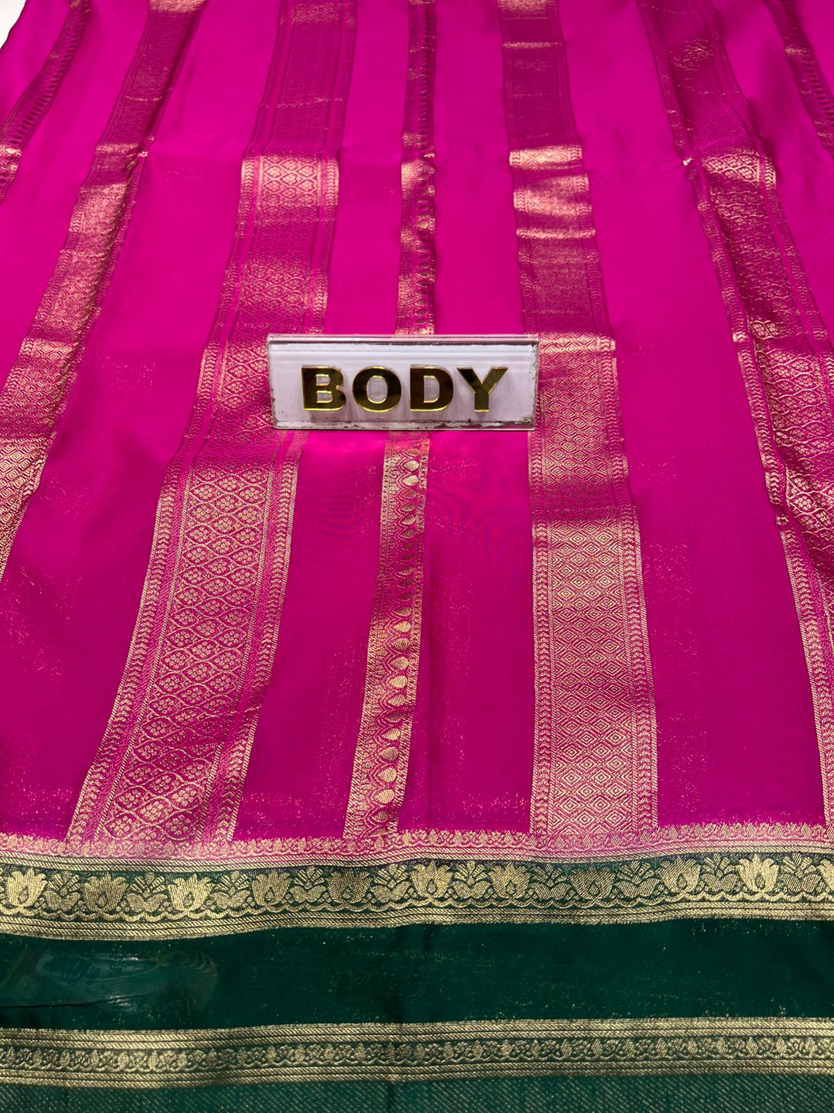Saree with a 'BODY' label on a pink and green fabric background