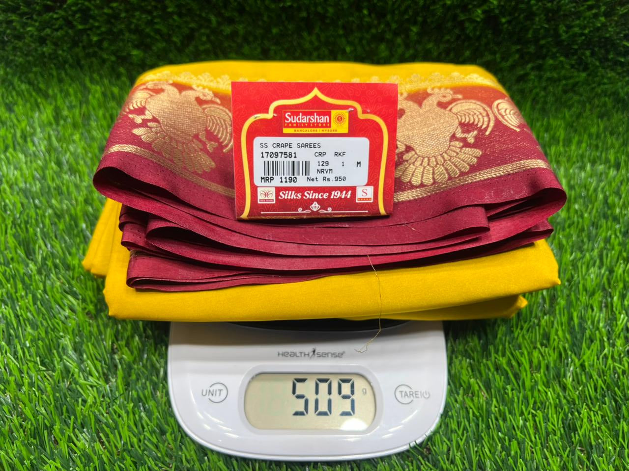 Yellow and red fabric with a digital scale on a green grass-like surface
