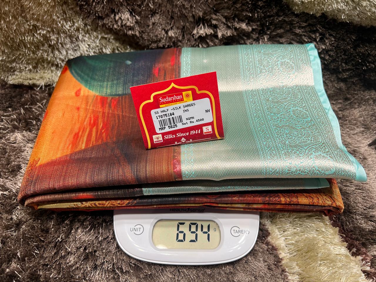Colorful fabric with a Swadkar label on a digital scale showing weight.