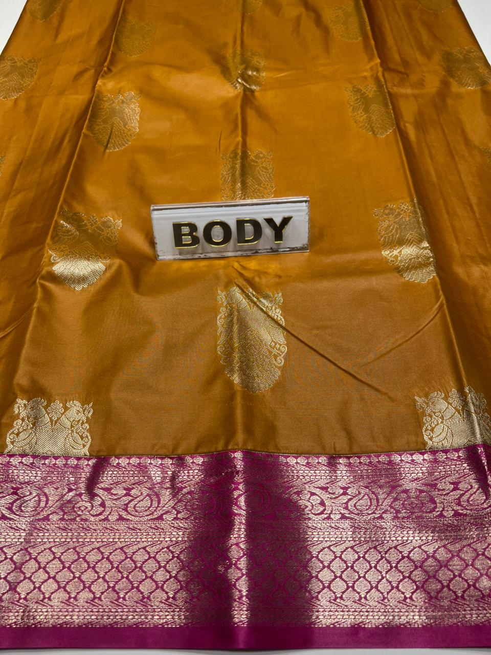 Brown fabric with gold and purple patterns and a label reading 'BODY'.