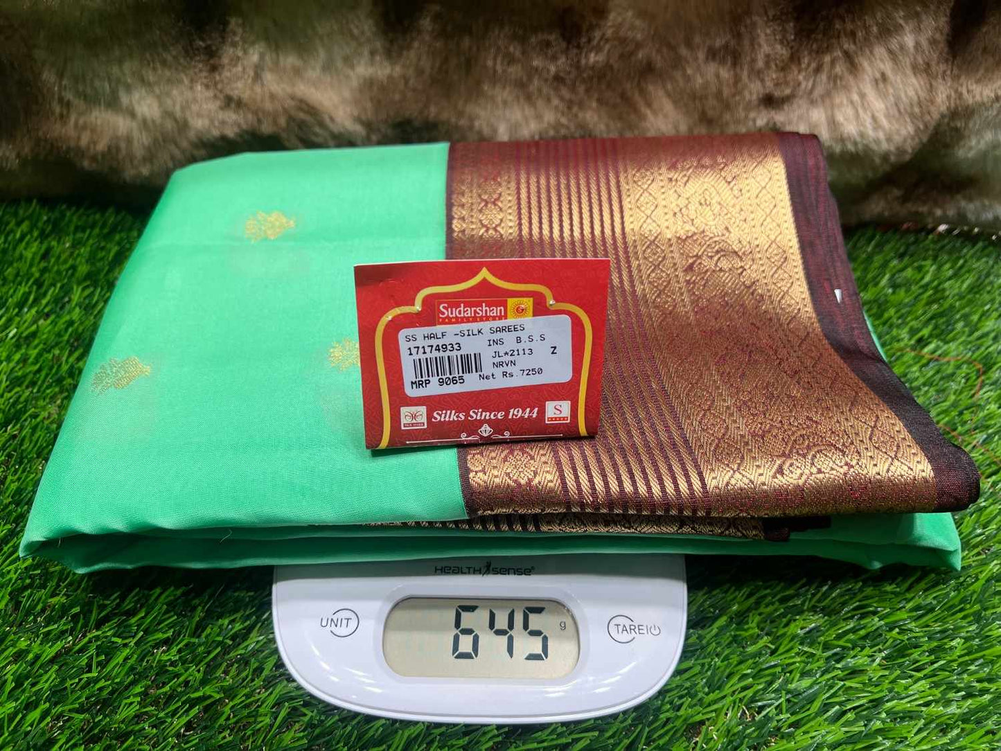 Green and gold saree with a label on a digital weight scale