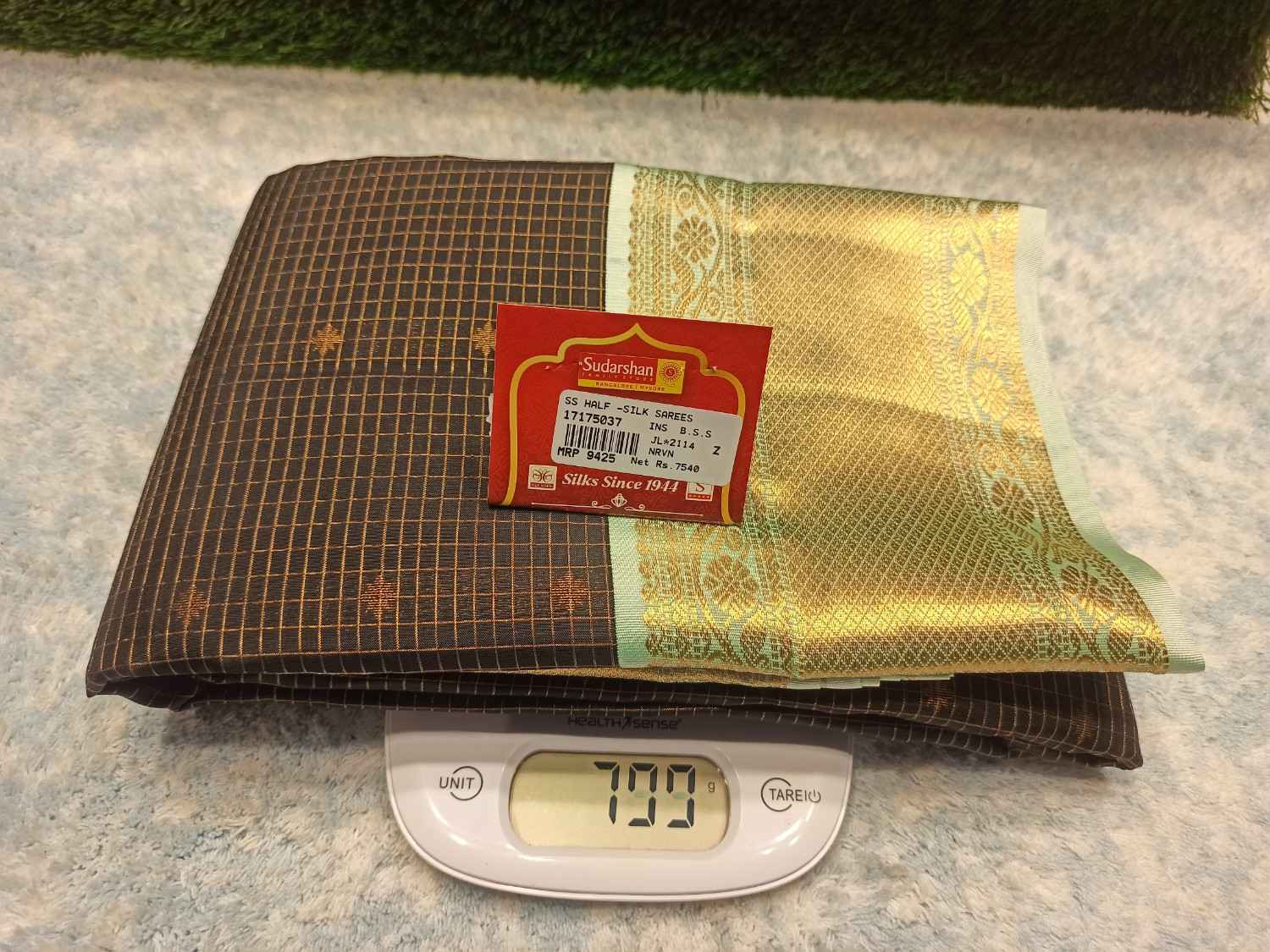 Gold foil sheet, Sadaam brand label, and digital scale on a textured surface