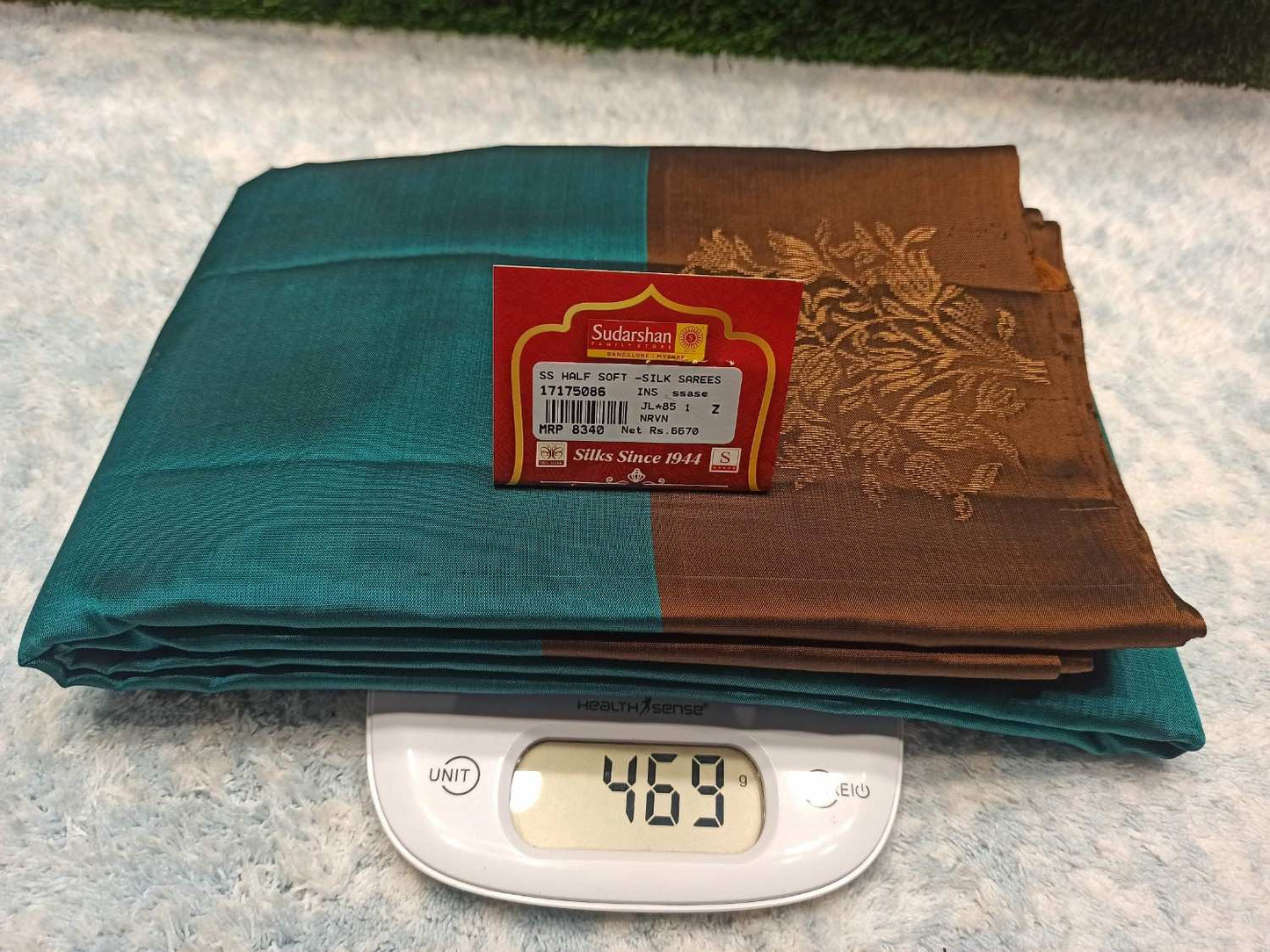 Stack of folded fabric with a label and digital scale showing weight on a textured surface