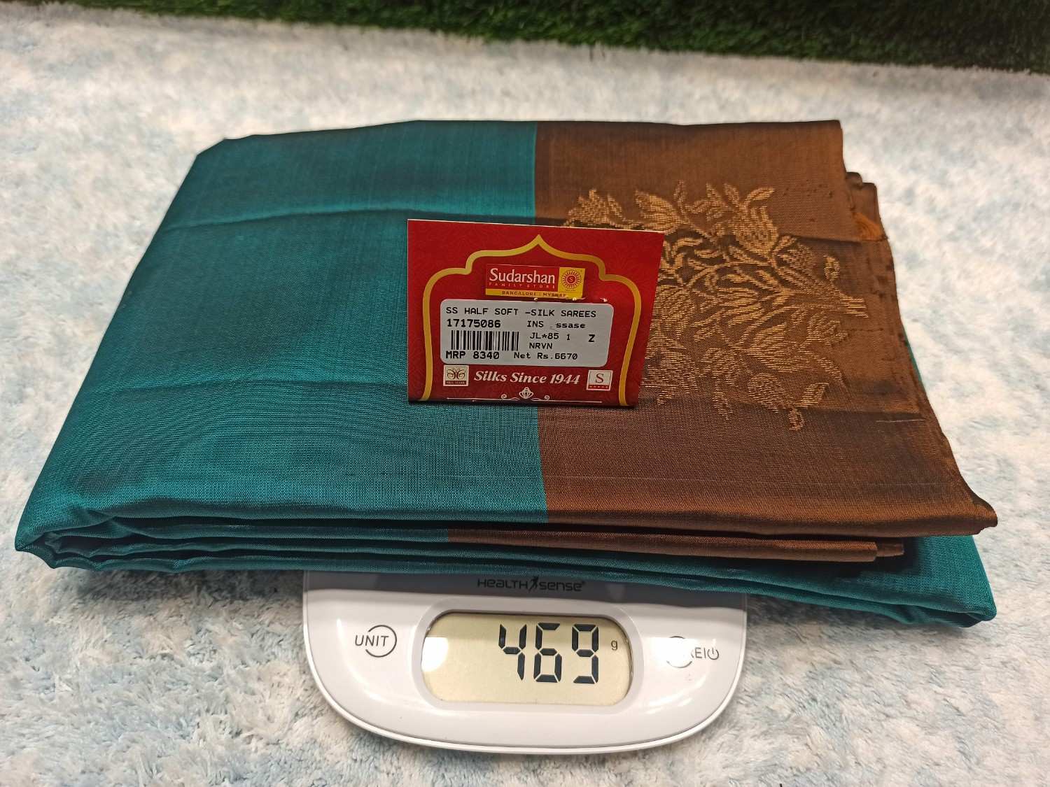 Stack of folded fabric with a label and digital scale showing weight on a textured surface