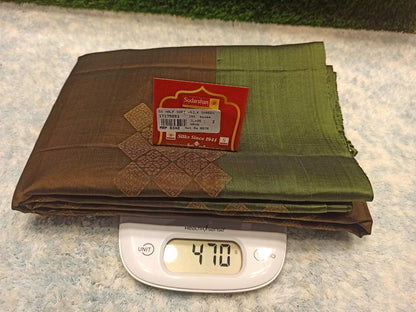 Folded brown and green fabric with a label on top of a digital scale showing weight.
