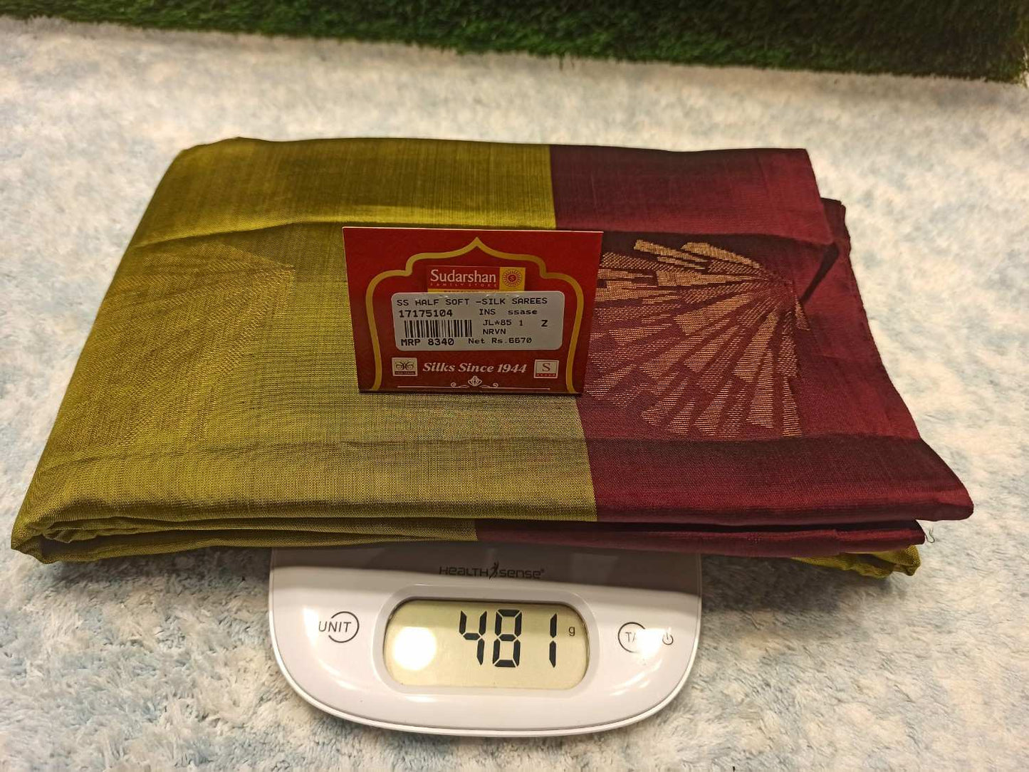 Two folded sarees on a digital scale with a visible brand label.