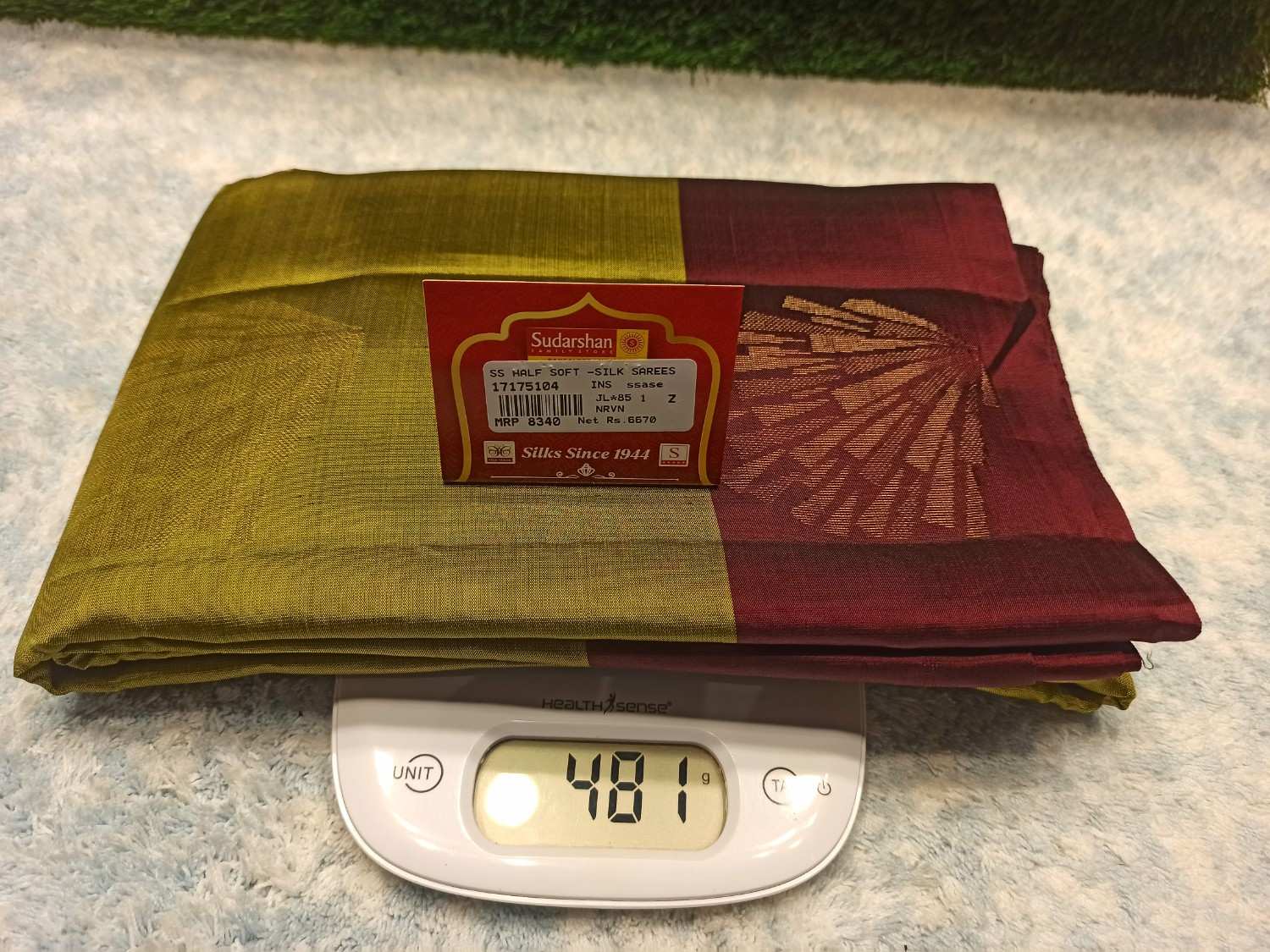 Two folded sarees on a digital scale with a visible brand label.