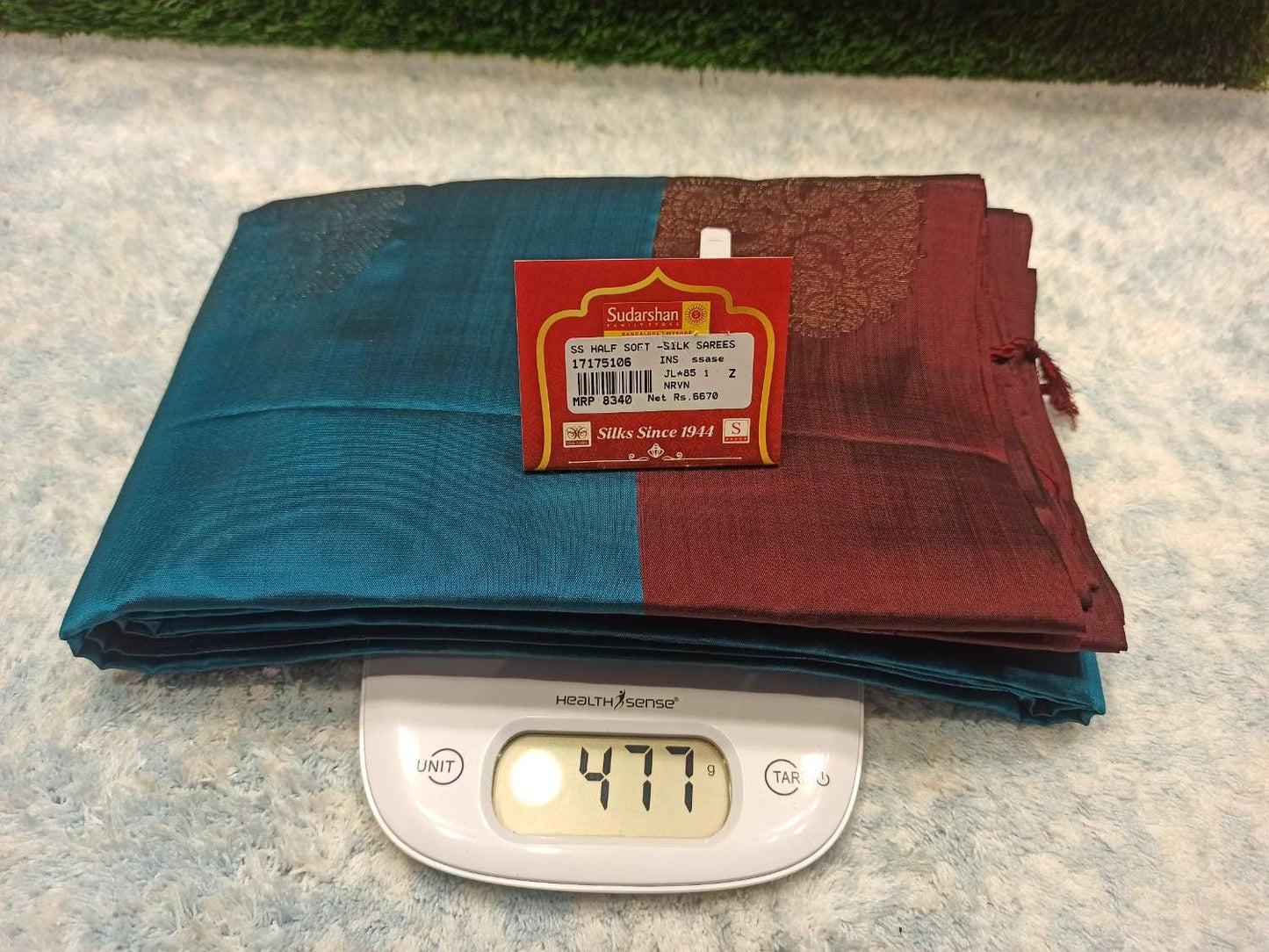 Two folded fabrics, one blue and one red, with a scale showing weight on a textured surface.