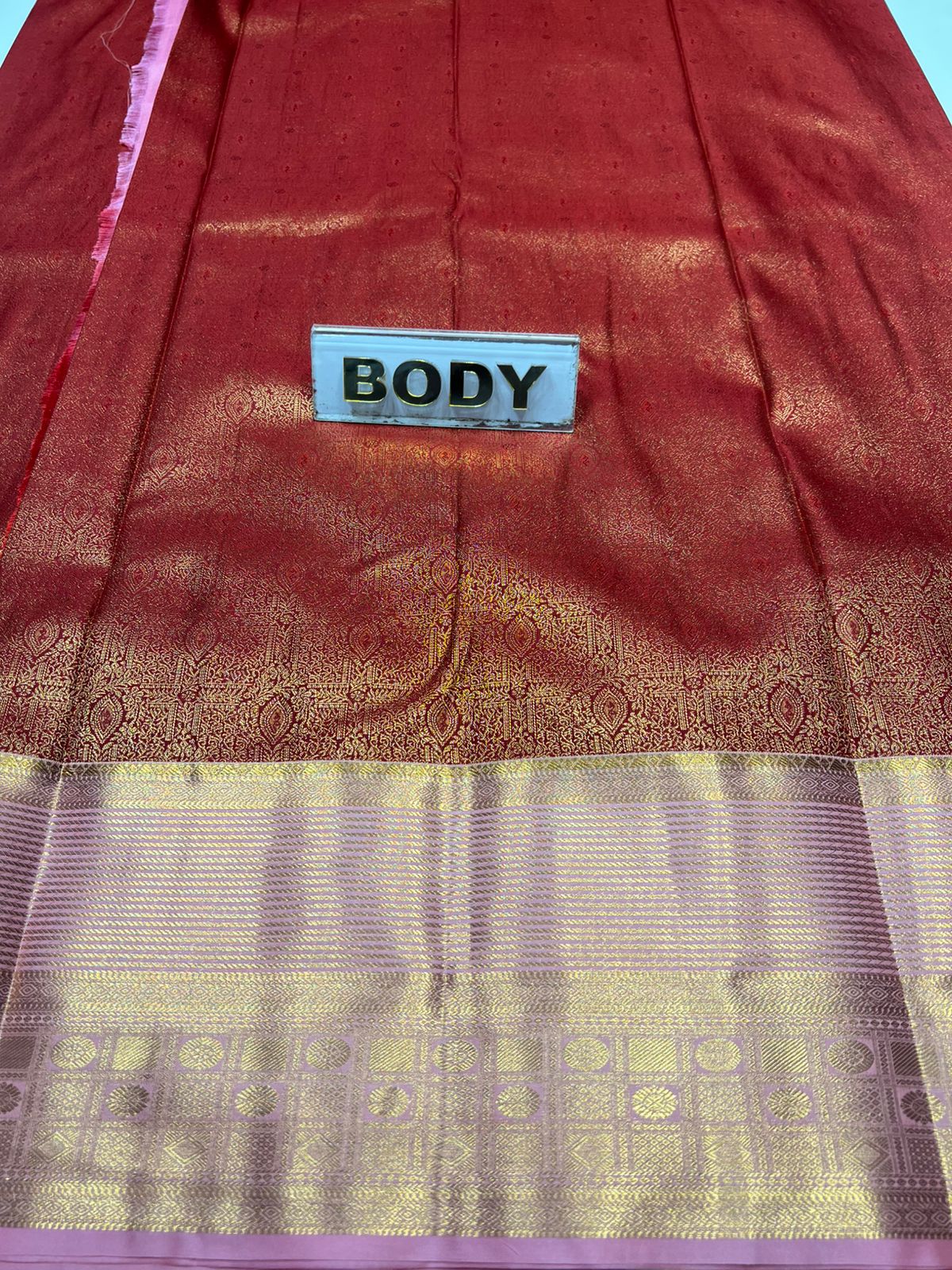 Red and gold saree with a 'BODY' label on a blue background