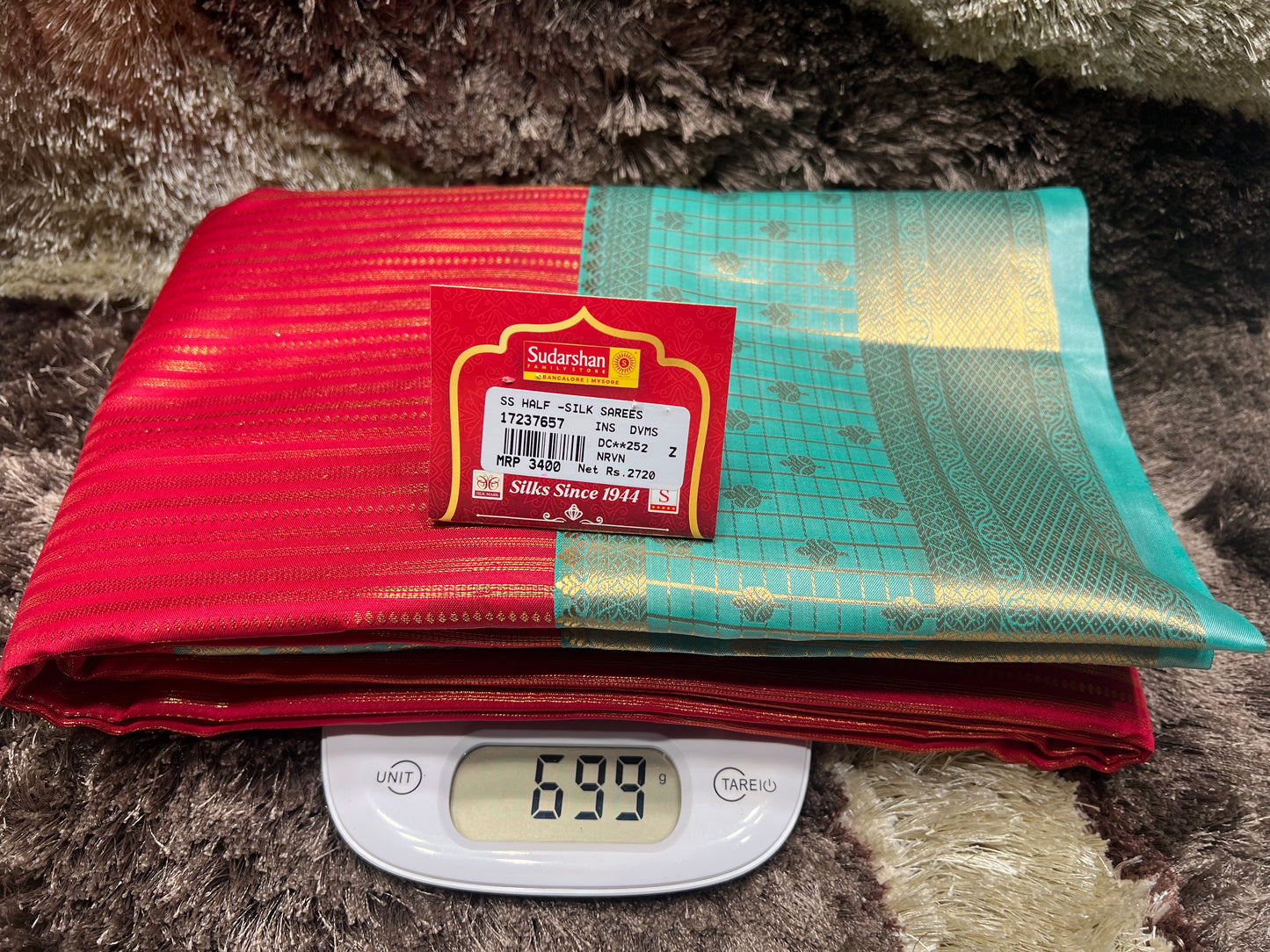 Stack of red and green fabric with a label on top of a digital scale showing weight.