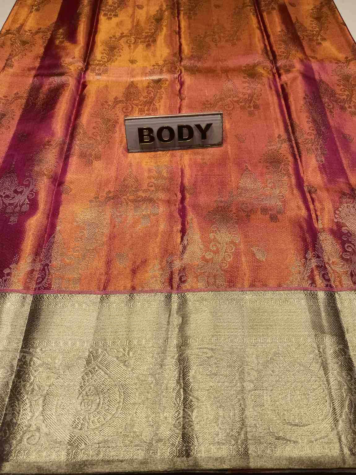 Decorative fabric with a 'BODY' label on an orange and gold patterned background