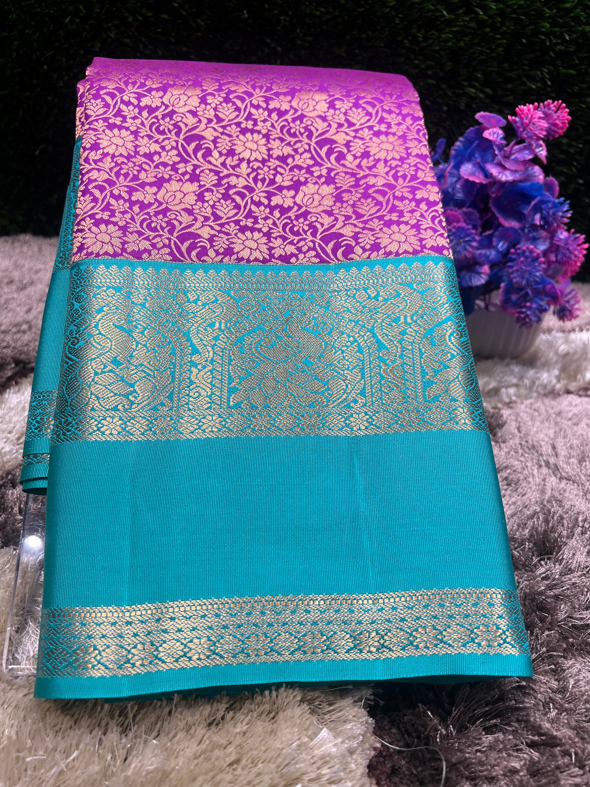 Teal and purple fabric with intricate patterns on a textured surface