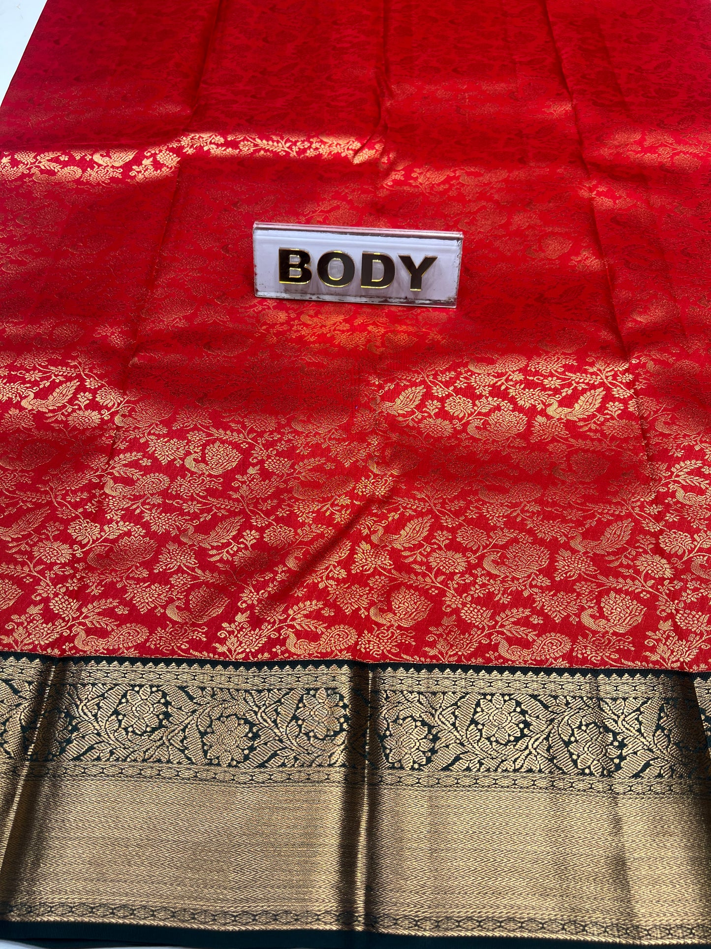 Red fabric with gold patterns and a 'BODY' label, next to black and gold patterned fabric.