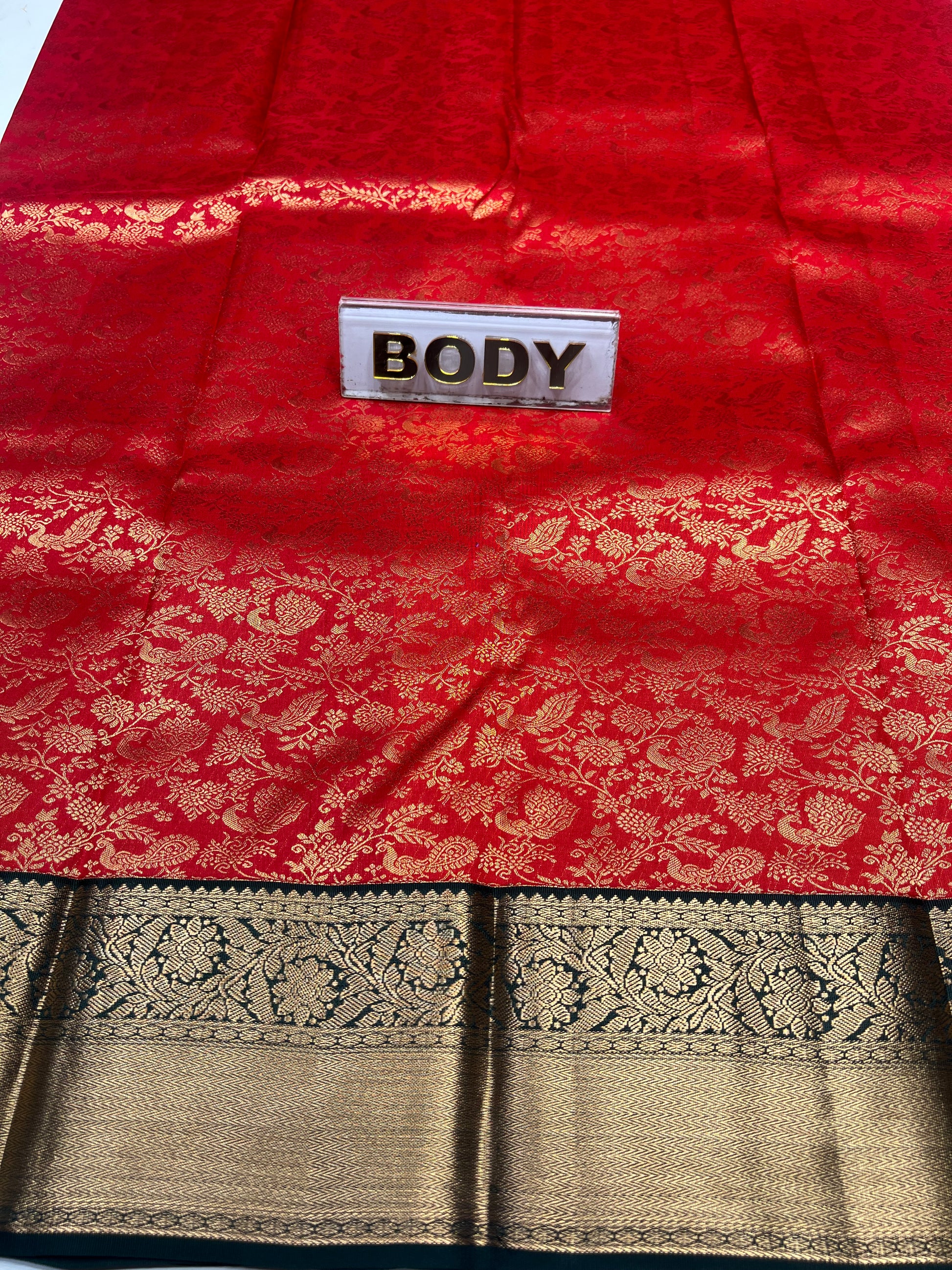Red fabric with gold patterns and a 'BODY' label, next to black and gold patterned fabric.