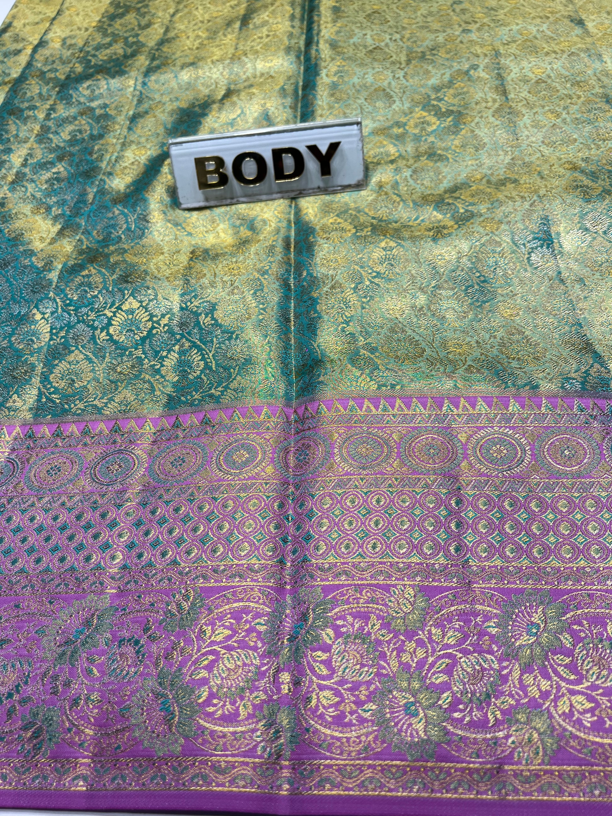 Textile with green and purple patterns labeled 'BODY' on a textured surface.