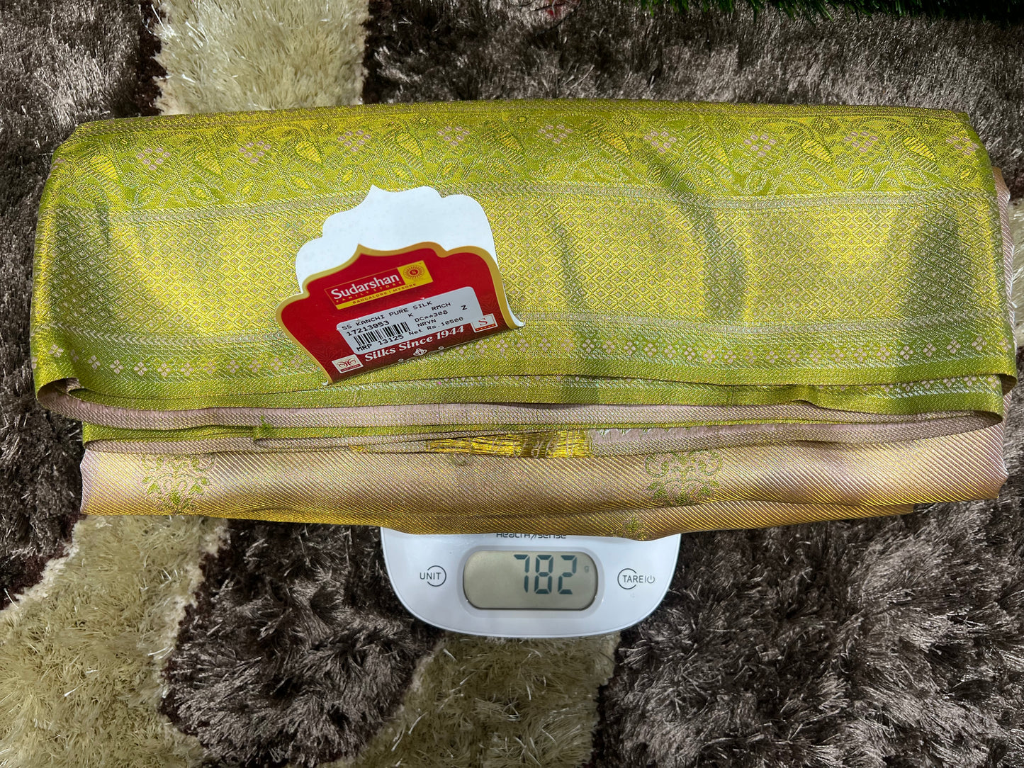 Green fabric with a tag on a digital scale against a textured brown background