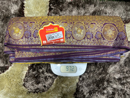 Purple and gold fabric roll with a label on a textured surface