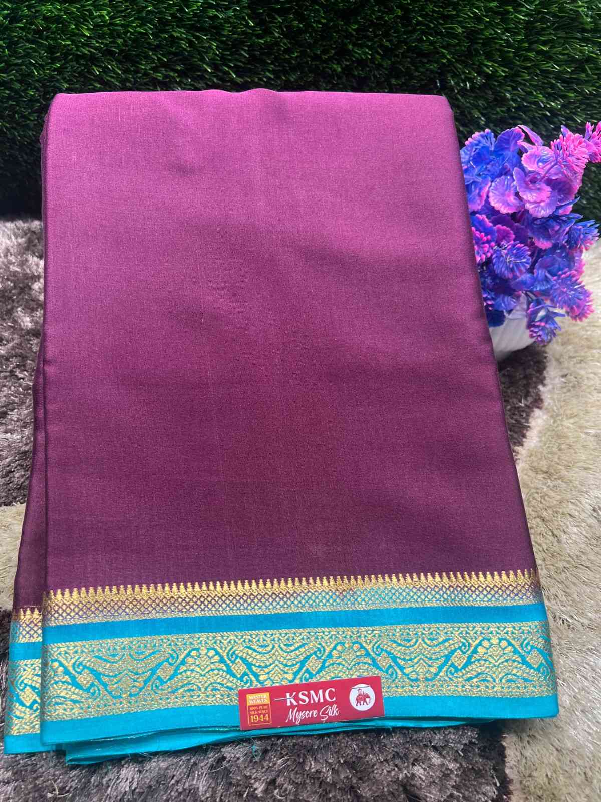 Purple saree with a blue border featuring KSMC logo on a textured surface.