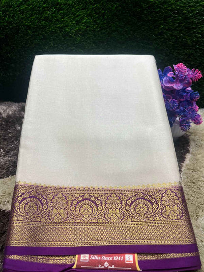 White saree with a purple and gold border on a textured surface with flowers in the background