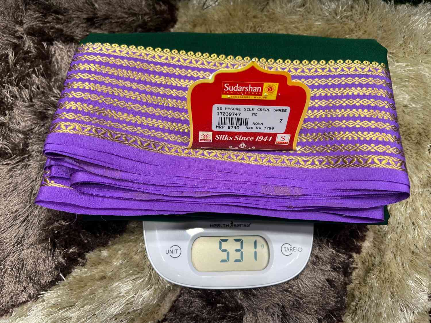 Purple fabric with gold patterns on a digital scale, branded 'Sudarshan'.