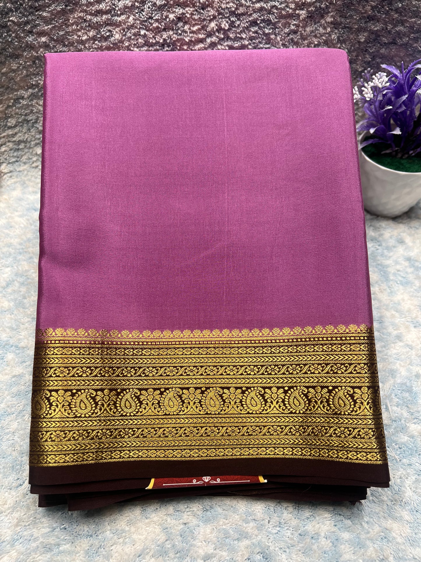 Purple fabric with gold and black border on a textured surface