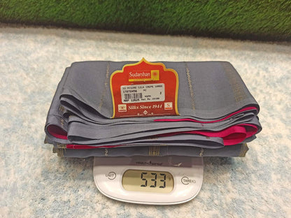 Stack of gray pants with a label on a digital scale showing weight, against a textured surface.