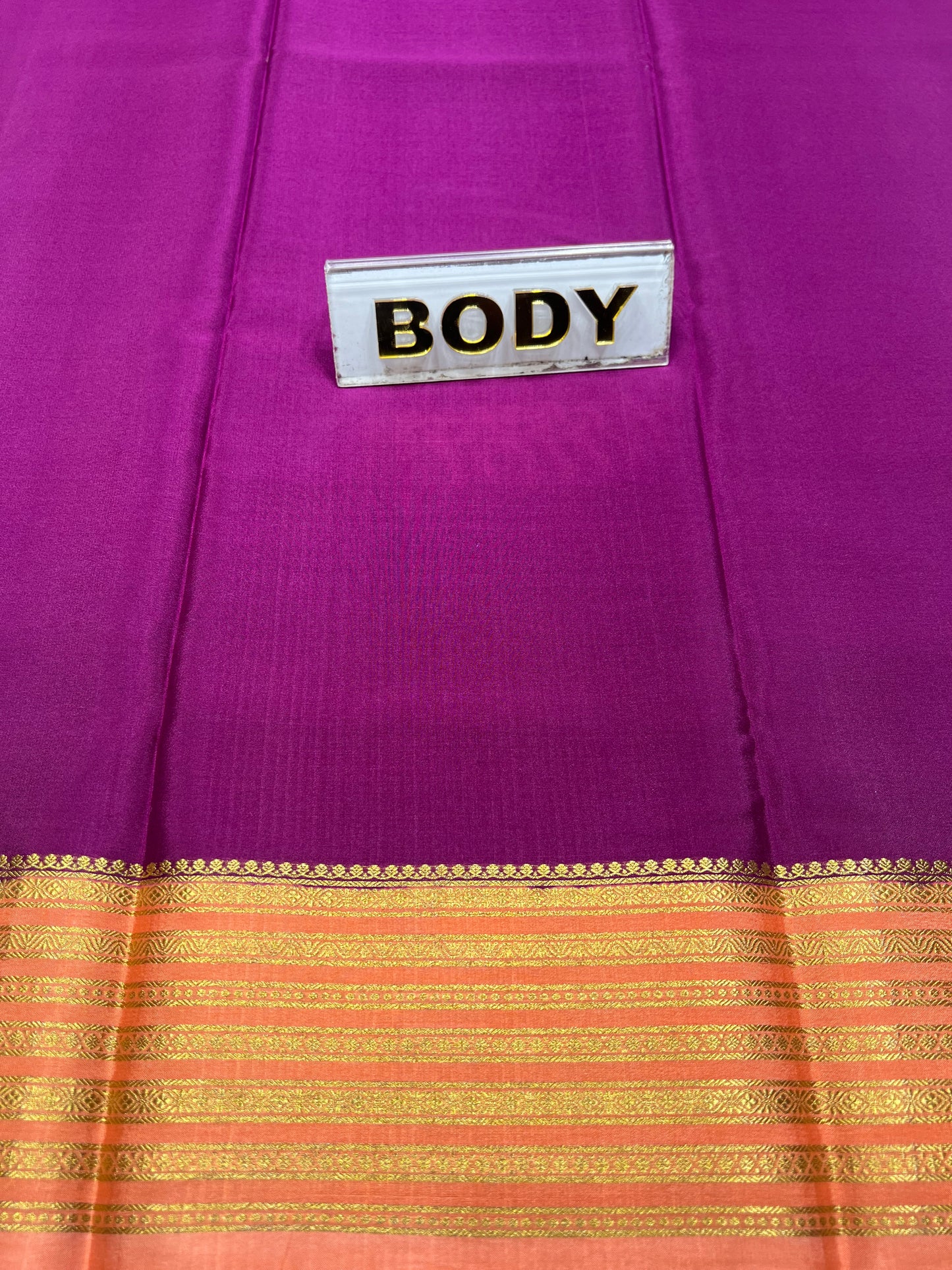 Purple fabric with a gold and orange border and a label reading 'BODY'.