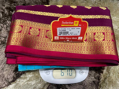 Stack of colorful sarees with a Sudarshan label on a digital scale