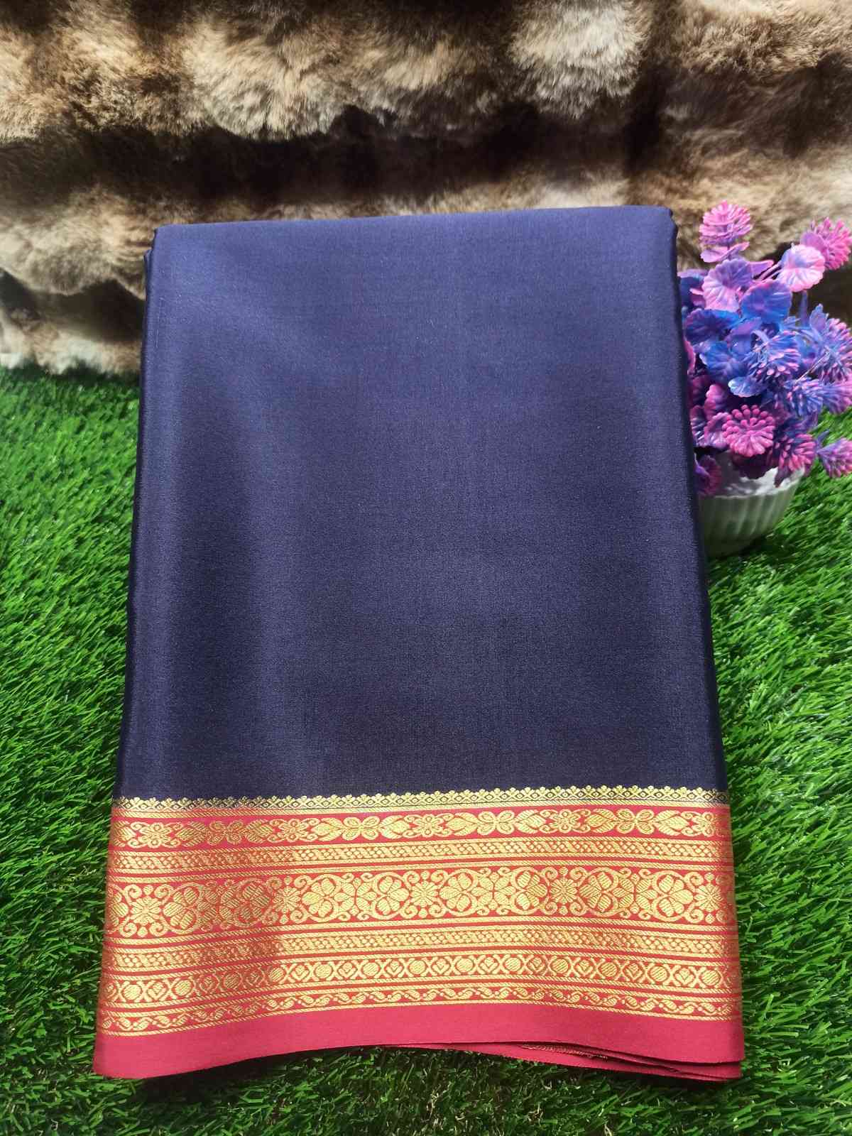 Navy blue fabric with a gold and red border on a grassy background