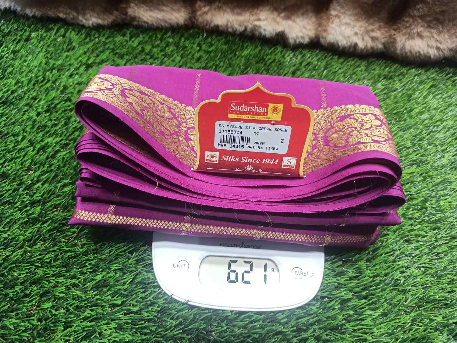 Purple fabric with a label on a digital scale against a grassy background