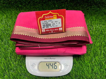 Pink fabric with a label on a green grass-like surface, next to a digital scale displaying 14.45 grams.