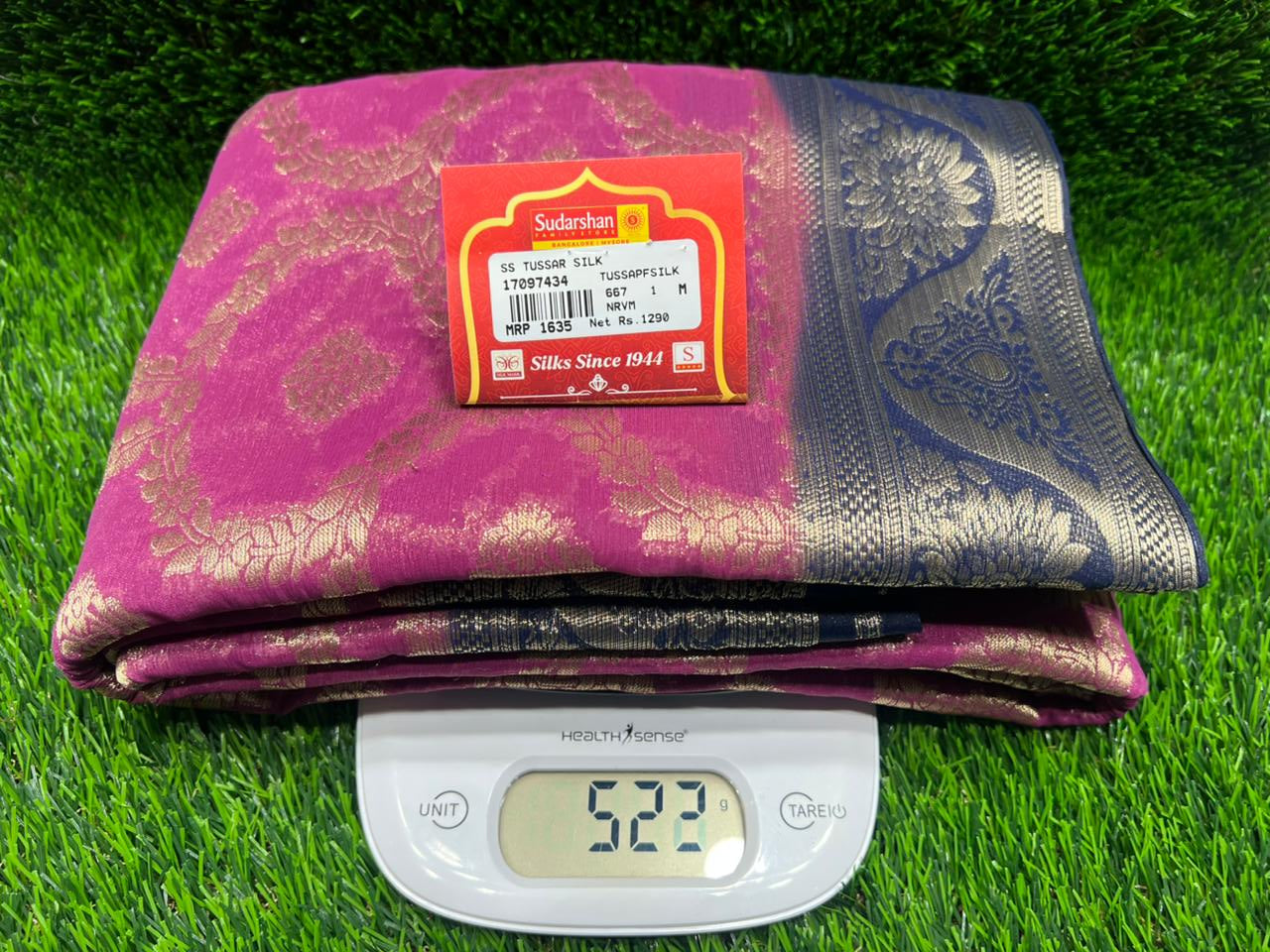 Folded fabric with a brand label on a digital scale against a grass background
