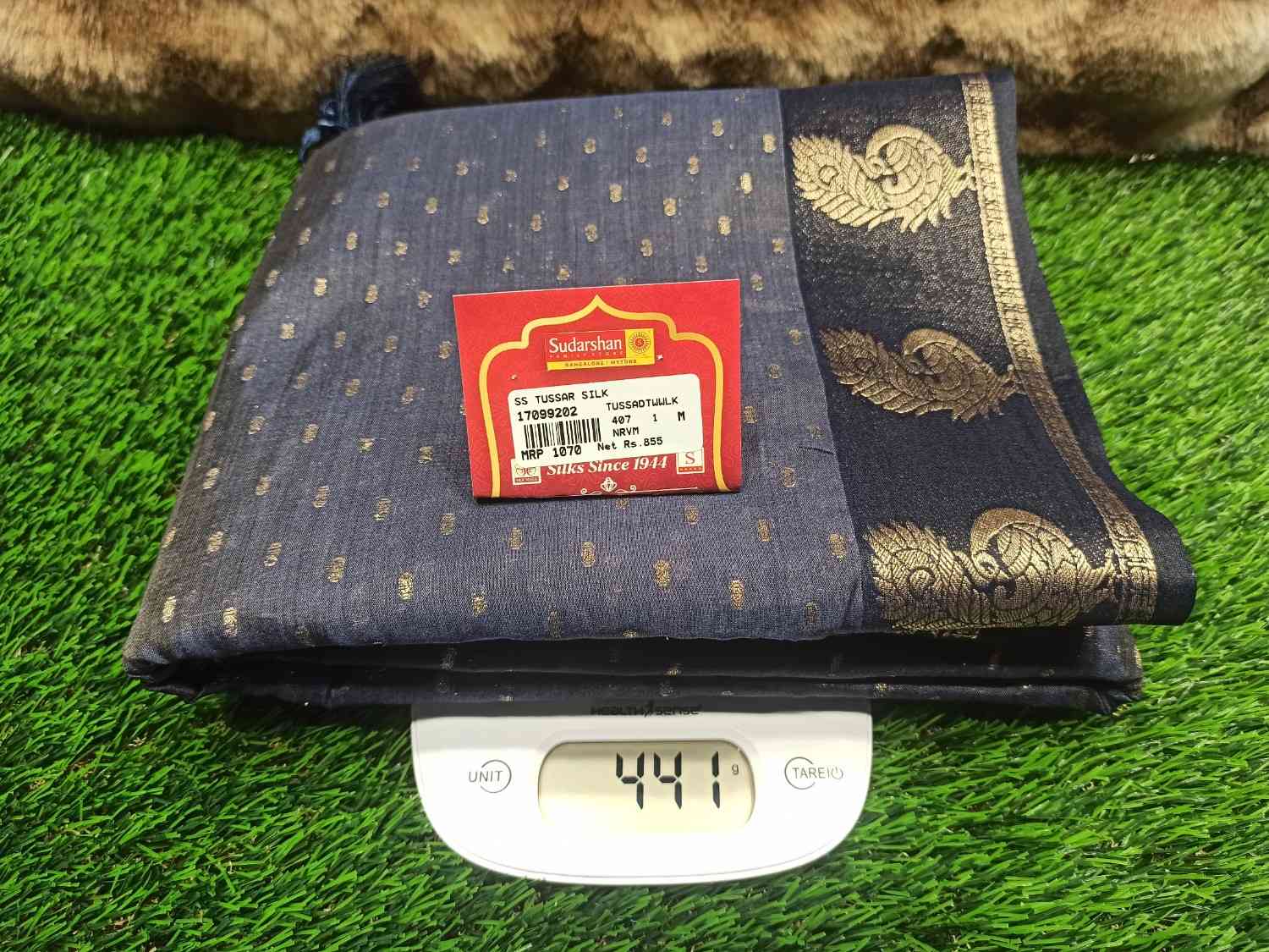 Folded fabric with a label on a digital scale against a grassy background