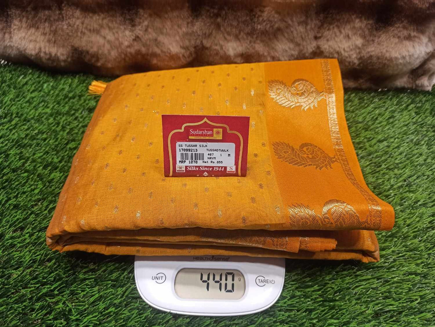 Yellow fabric with a brand label on a digital scale against a grassy background