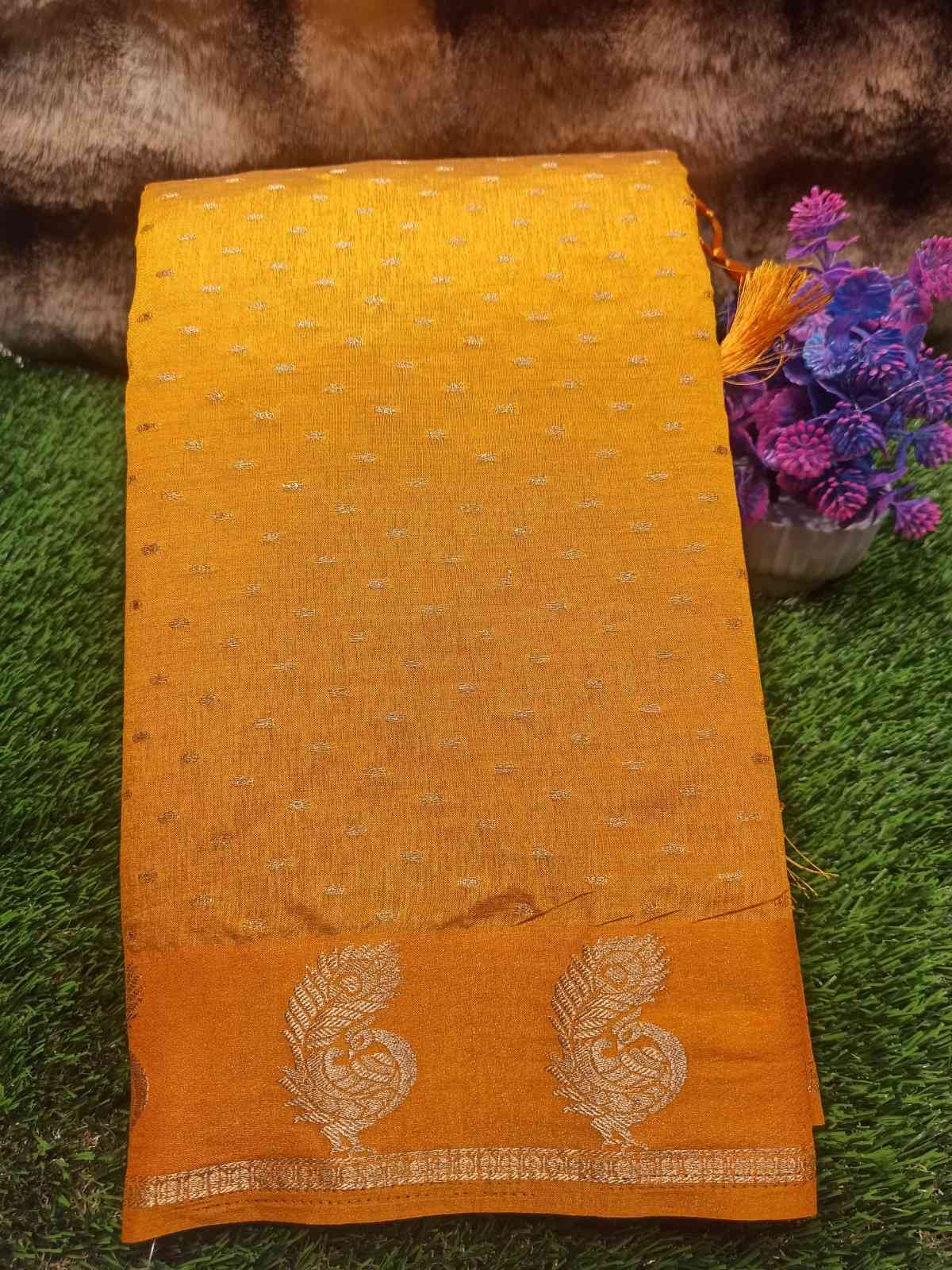 Yellow fabric with floral patterns on a green surface with flowers in the background