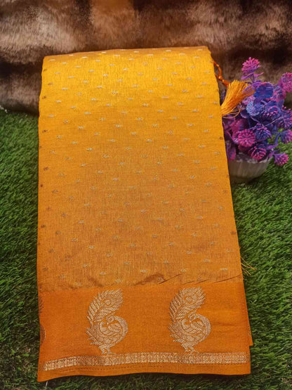 Yellow fabric with floral patterns on a green surface with flowers in the background