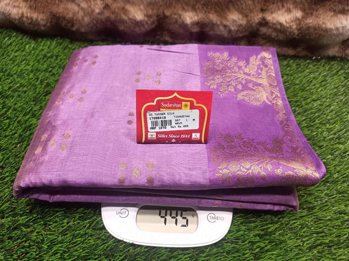 Purple fabric with gold patterns on a digital scale against a green grass background