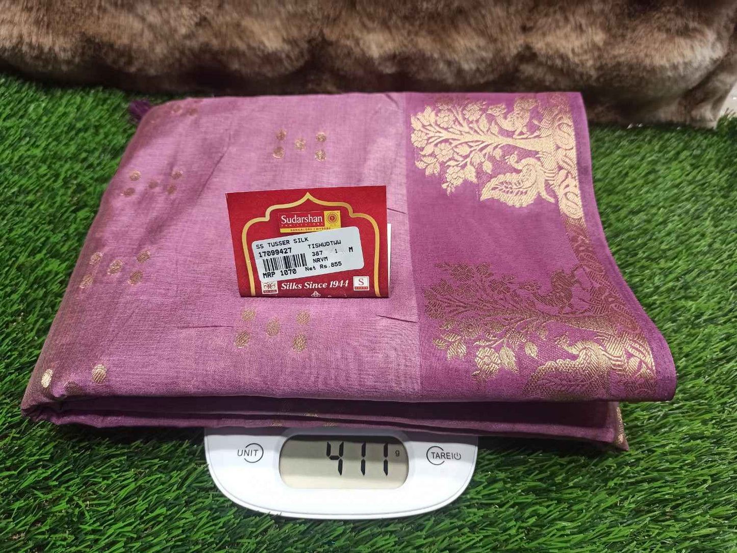 Purple fabric with gold patterns on a digital scale against a grassy background