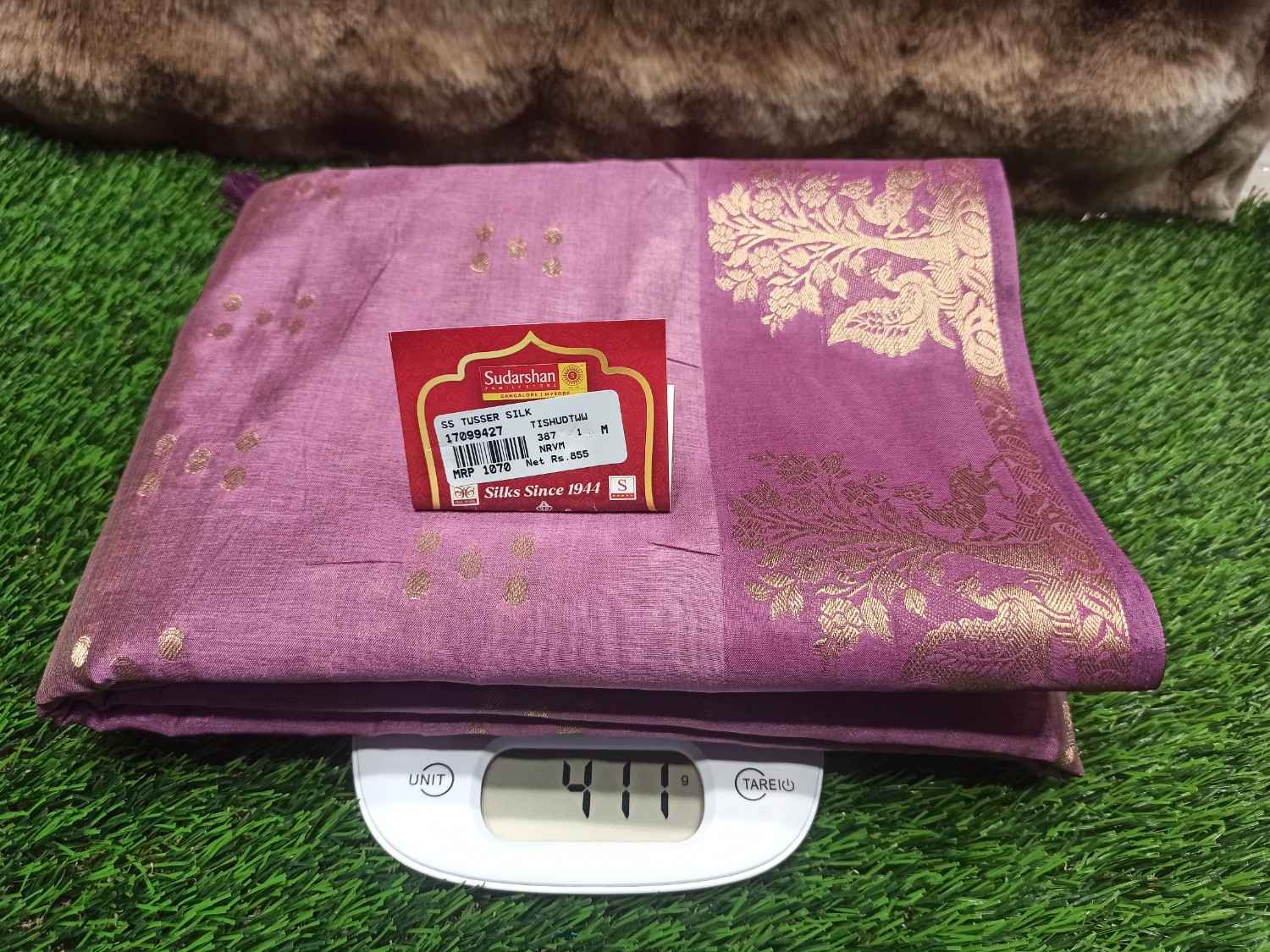 Purple fabric with gold patterns on a digital scale against a grassy background