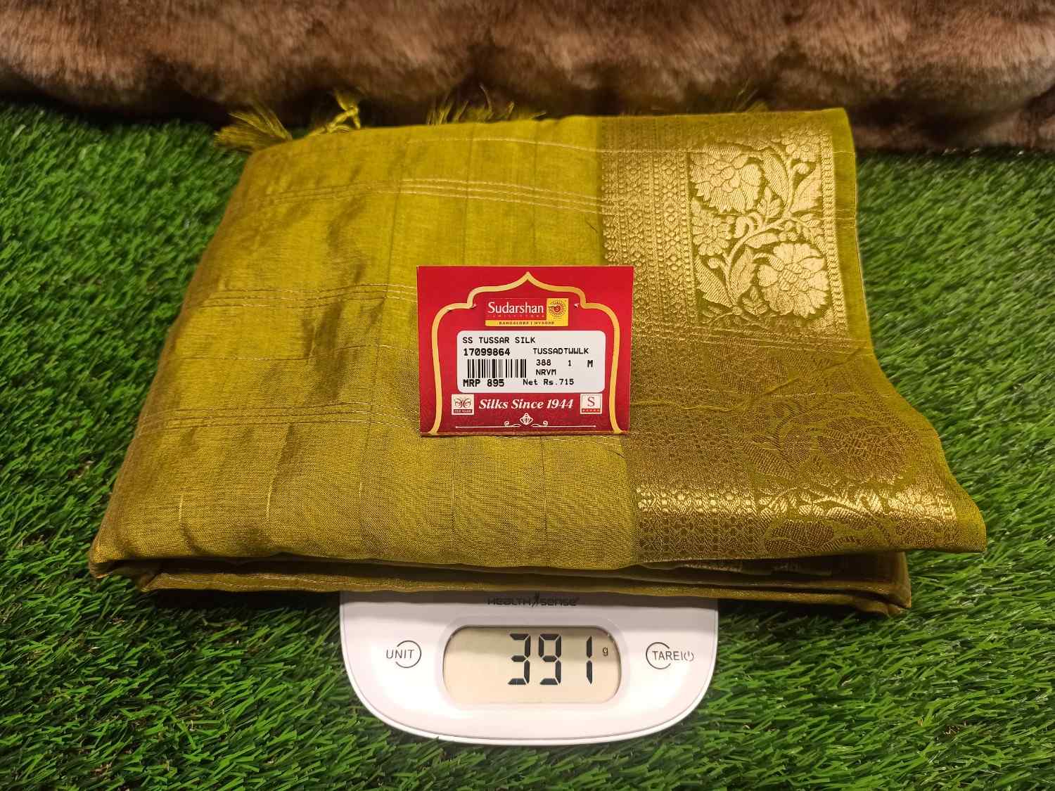 Green fabric with a label on a digital scale against a grassy background