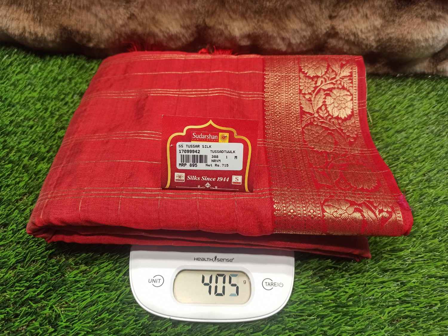 Red fabric with a label on a digital scale against a grass background
