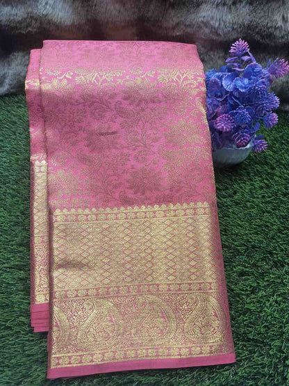 Pink and gold traditional fabric with intricate patterns on a green surface.