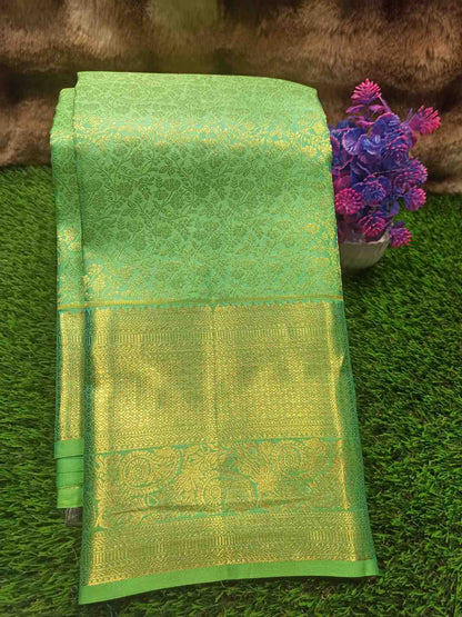 Green and gold saree with floral decoration on a grassy background